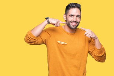 Tecrit edilmiş, güler yüzlü, kendine güvenen, parmaklarını, dişlerini ve ağzını gösteren genç yakışıklı bir adam. Sağlık kavramı.