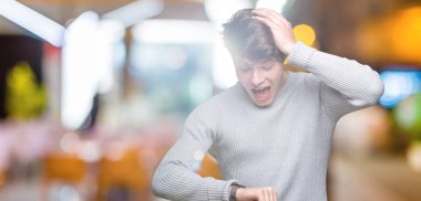 Genç yakışıklı adam giyen kış kazak izole arka plan üzerinde seyretmek zaman endişeli, geç korkuyor arıyorsunuz