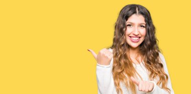 Beyaz kazak giyen genç güzel kadın kendinden emin gülümseyen arkasından el ve kadar başparmak ile işaret