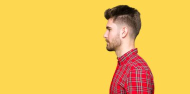 Yandan bakan yakışıklı bir genç, rahat profil pozu, doğal bir yüz ve kendine güvenen bir gülümseme..