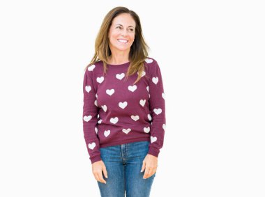 Üzerinde kalpler kazak giyen güzel orta yaş kadın arka plan uzak tarafına gülümseme ile yüzünde, doğal ifade arıyorum izole. Kendine güvenen gülüyor.