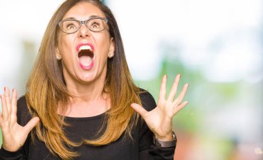 Güzel orta yaş kadın çılgın ve kızgın bağırarak ve agresif ifade ve silah kaldırdı bağırmaya gözlüklü. Hayal kırıklığı kavramı.