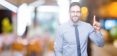 Ve parmak gülümseyen süre bir numara ile kendinden emin ve mutlu yukarıyı gösteren izole arka plan üzerinde gözlük takan genç iş adamı.