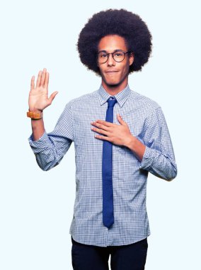 Young african american business man with afro hair wearing glasses Swearing with hand on chest and open palm, making a loyalty promise oath clipart