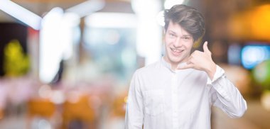 Genç yakışıklı iş adamı yapıyor gülümseyen izole arka plan üzerinde telefon hareketi ile el ve parmak telefonda konuşuyor gibi. Kavramları iletişim.