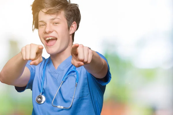 分離上医療制服を着て若い医者の背景を指すと指でカメラ肯定的な陽気な笑顔 — ストック写真
