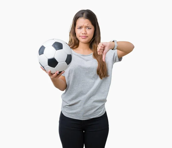 年轻美丽的黑发女子拿着足球在孤立的背景与愤怒的脸 消极的迹象显示不喜欢大拇指下来 拒绝的概念 — 图库照片