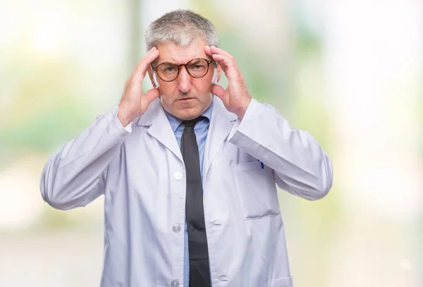 Handsome senior doctor, scientist professional man wearing white coat over isolated background with hand on head for pain in head because stress. Suffering migraine.