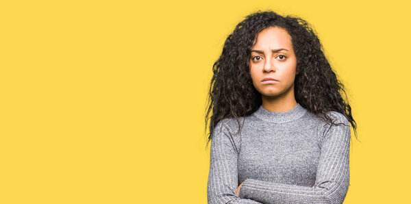 Young beautiful girl with curly hair skeptic and nervous, disapproving expression on face with crossed arms. Negative person.