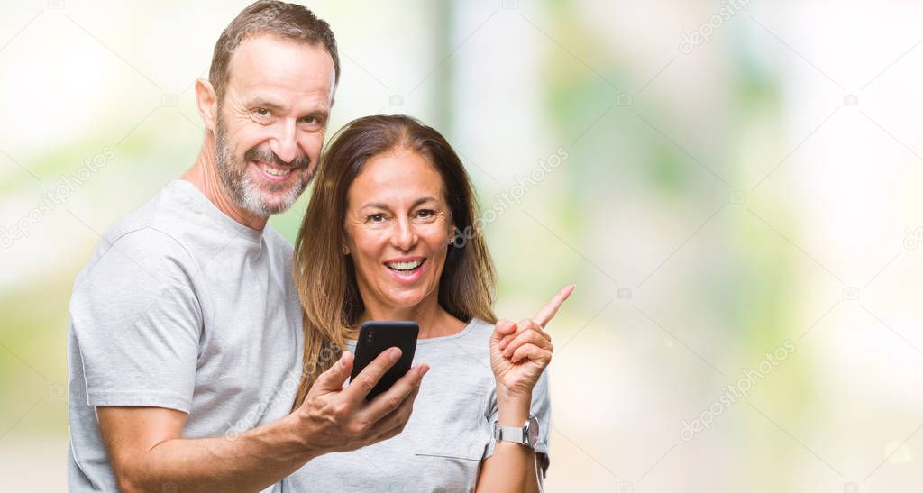 Middle age hispanic couple texting message on smartphone ver isolated background very happy pointing with hand and finger to the side