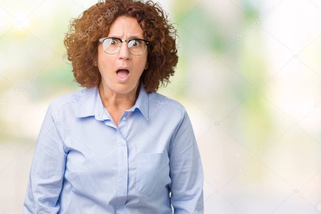 Beautiful middle ager senior businees woman wearing glasses over isolated background afraid and shocked with surprise expression, fear and excited face.