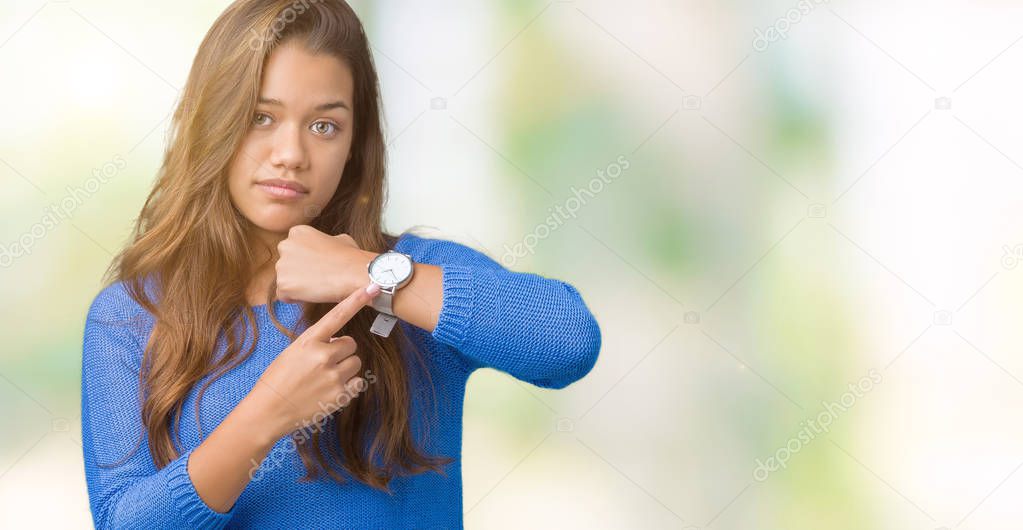 Young beautiful brunette woman wearing blue sweater over isolated background In hurry pointing to watch time, impatience, upset and angry for deadline delay