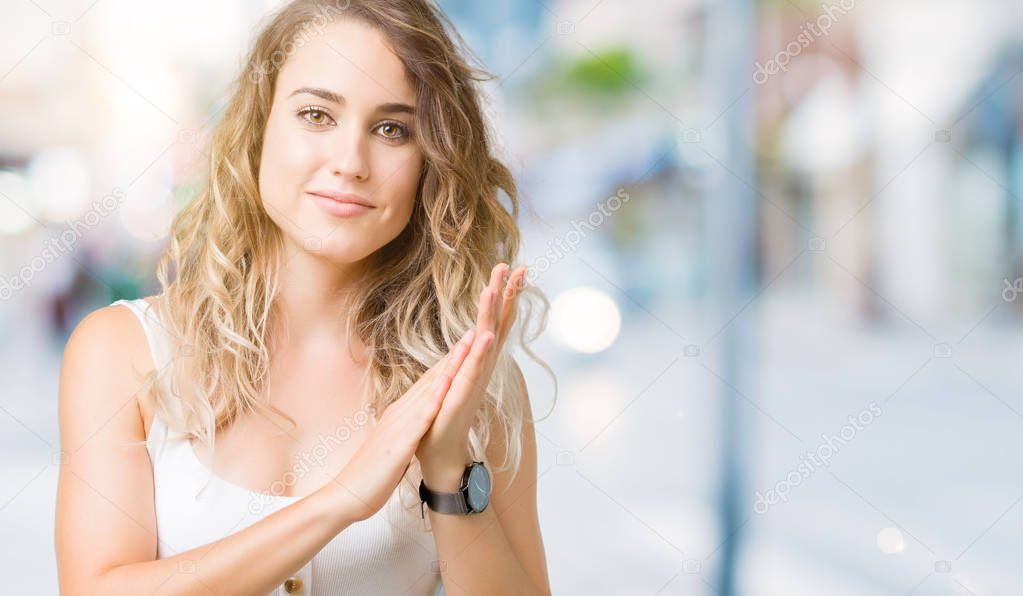 Beautiful young blonde woman over isolated background Clapping and applauding happy and joyful, smiling proud hands together