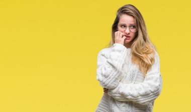 Kış kazak ve güneş gözlüğü stresli ve gergin elle çivi ısırma ağzına bakarak izole arka plan üzerinde giyen genç güzel sarışın kadın. Anksiyete sorunu.