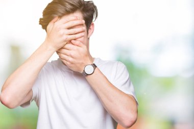 Yakışıklı delikanlı izole arka plan kaplaması gözler ve ağız el ile üzerinden Casual beyaz t-shirt giyen şaşırttı ve şok. Duygu gizleme