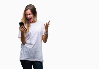 Smartphone üzerinde kocaman bir gülümseme ile çığlık zaferini kutluyor ve ellerini kaldırdı izole arka plan çok mutlu ve heyecanlı, kazanan ifade kullanan genç güzel sarışın kadın