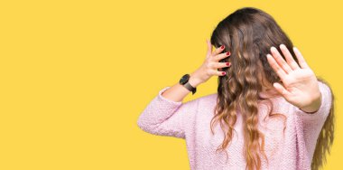 Pembe kazak kapsayan giyen genç güzel kadın gözleri ile el ve stop jest ile acı ve korku ifadesi. Utandım ve negatif kavramı.