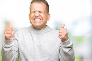 Orta yaş Arap adam izole arka kolları olan başarı için heyecan üzerinde spor kazak giyen zafer kutluyor gülümseyen kaldırdı. Kazanan kavramı.