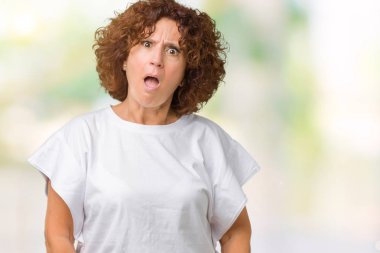 Beyaz giyen güzel orta ager üst düzey kadın şüpheci ve alaycı, t-shirt üzerine şok karşısında izole arka plan açık ağız ile şaşırttı.