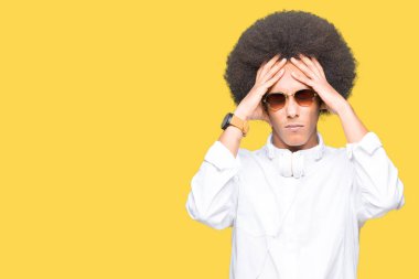 Güneş gözlüğü ve kulaklık çünkü umutsuz ve stresli baş ağrısı acı afro saçlı genç Afro-Amerikan adam ağrı ve migren. Ellerini kafasına.