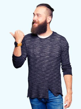 Seyir ve başparmak yanında yukarıyı mutlu yüz ile gülümseyen rahat kazak giyen genç sarışın adam.