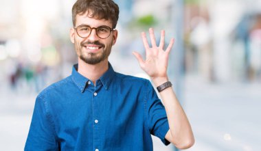 Gösterilen arka plan üzerinde gözlük takan genç yakışıklı adam izole ve parmakları ile işaret kendinden emin ve mutlu gülümseyerek süre beş numara.