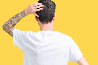 İzole arka plan geriye düşünme hakkında şüphe kafasına el ile üzerine beyaz t-shirt giyen genç yakışıklı adam