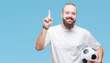 Futbol futbol topu izole arka plan üzerinde bir fikir ya da soru işaret parmağı gülen yüz, bir numara ile sürpriz tutan genç beyaz hipster adam