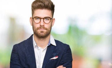 Yüz çapraz kolları üzerinde gözlük şüpheci ve sinir, onaylamayan ifade giyen genç yakışıklı iş adam. Negatif kişi.