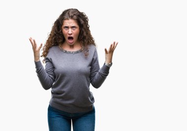 Güzel esmer kıvırcık saçlı Genç kız izole arka plan çılgın ve kızgın bağırarak ve agresif ifade ve silah kaldırdı bağırıyor bir kazak giyiyor. Hayal kırıklığı kavramı.