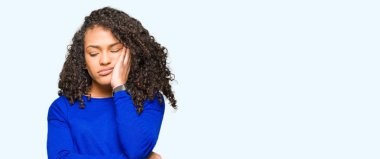 Kıvırcık saçlı kış kazak düşünme seyir giyen genç güzel kadın yorgun ve sıkılmış çapraz silah depresyon sorunları ile.