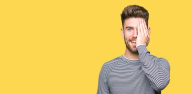 El yüz ve sürpriz duygu kendinden emin gülümseme ile kazak kapsayan tek gözlü yakışıklı delikanlı giyen çizgili.