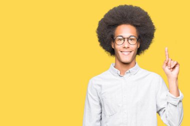 Afro saçlı gösterilen ve kendinden emin ve mutlu gülümseyen bir parmak ile işaret eden oktan yukarı gözlüklü genç Afro-Amerikan adam.