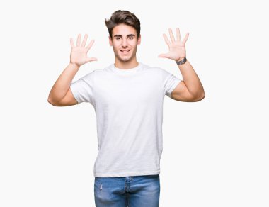 Gösterilen ve parmakları ile işaret izole arka plan üzerinde beyaz t-shirt giyen genç yakışıklı adam kendinden emin ve mutlu gülümseyerek süre on numara.