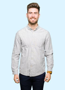 Yüzünde mutlu ve havalı bir gülümseme olan sıradan bir gömlek giyen genç yakışıklı bir adam. şanslı kişi.