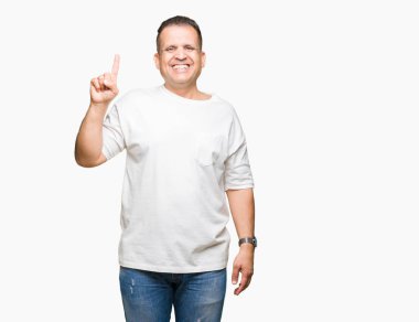 Orta yaş Arap adam wearig gösterilen ve kendinden emin ve mutlu gülümseyen bir parmak ile işaret eden oktan yukarı arka plan beyaz t-shirt üzerine izole.
