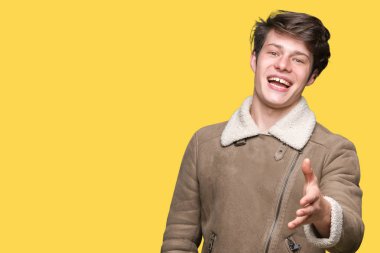 Üzerinde kış ceket giyen genç yakışıklı adam arka plan olarak tebrik ve konuksever dost sunan karşılıklı gülümseyen izole. Başarılı iş.