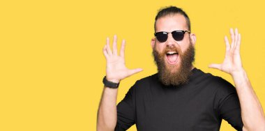 Genç hipster adam çılgın ve kızgın bağırarak ve agresif ifade ve silah kaldırdı bağırmaya güneş gözlüğü takıyor. Hayal kırıklığı kavramı.