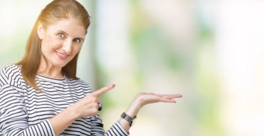 Üzerinde çizgili kış kazak giyen orta yaş olgun güzel kadın arka plan gösteren palm el ve iş tamam jestle başparmak yukarıya, mutlu ve neşeli gülümseyen izole