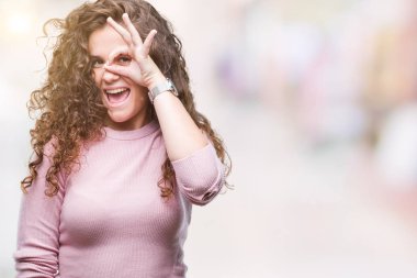 Güzel esmer kıvırcık saçlı Genç kız gülümsüyor, parmakları ile mutlu yüz üzerinden seyir göz el ile ok jest yapıyor izole arka plan üzerinde pembe kazak giyiyor.