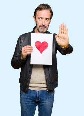 Açık eliyle dur işareti ile ciddi ve kendine güvenen ifade, savunma jest yapıyor kırmızı kalp ile kağıt tutan yakışıklı orta yaş erkek