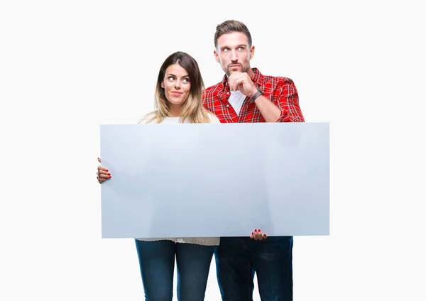 Young Couple Together Holding Blank Banner Isolated Background Serious Face — Stock Photo, Image