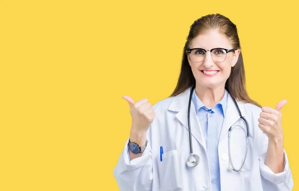 中年成熟的医生妇女穿着医疗外套在孤立的背景成功标志做积极的手势用手 竖起大拇指微笑和快乐 带着欢快的表情 获胜者的手势看着镜头 — 图库照片