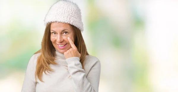 美丽的中年妇女穿着冬季毛衣和帽子在孤立的背景指向眼睛看着你的手势 可疑的表情 — 图库照片