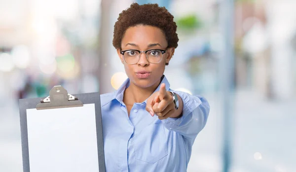 若いアフリカ系アメリカ人ビジネス女性持株クリップボード カメラと指で指している孤立した背景に 手に署名 正面からポジティブで自信のジェスチャー — ストック写真
