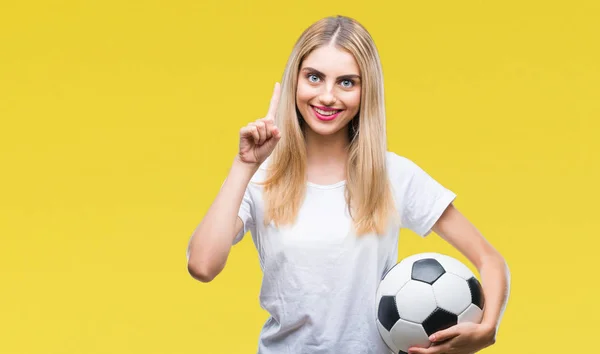 年轻美丽的金发碧眼的女人拿着足球在孤立的背景惊讶的想法或问题用快乐的脸指指点点 — 图库照片