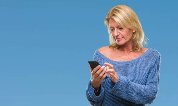 Middle age blonde woman sending message using smartphone over isolated background with a confident expression on smart face thinking serious