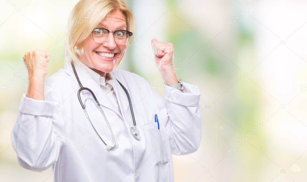 Middle age blonde doctor woman over isolated background very happy and excited doing winner gesture with arms raised, smiling and screaming for success. Celebration concept.