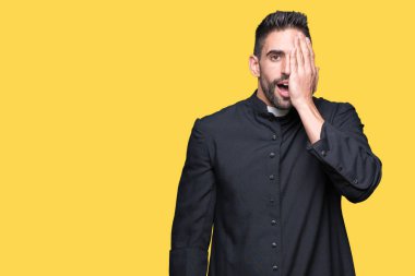 Genç Hıristiyan rahip el yüz ve sürpriz duygu kendinden emin gülümseme ile tek gözüyle kapsayan izole arka plan üzerinde.