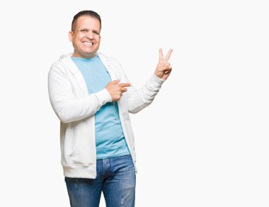 Mutlu yüz zafer işareti yaparken kameraya göz kırpıyor ile gülümseyen izole arka plan üzerinde sweatshirt giyen orta yaş Arap adam. İki numaralı.